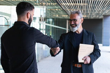Smiling male entrepreneurs doing handshake at entrance