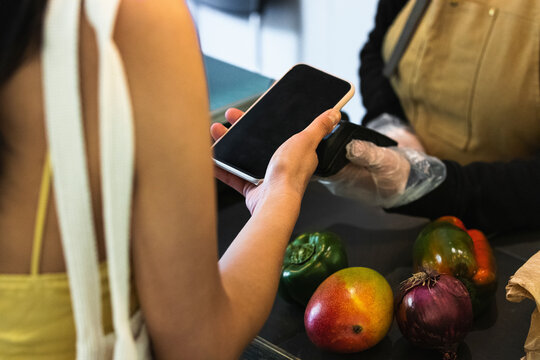 Woman Paying Through Mobile Phone At Grocery Store