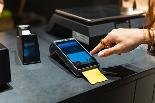 Female customer entering password on reader while paying through credit card at retail shop