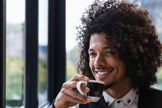 Handsome male businessman looking away while having coffee in cafe