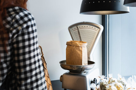 Young woman measuring ingredient on weight scale at store