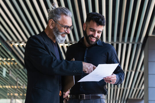 Smiling businessman explaining business plan to male colleague at entrance