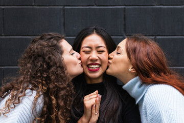 Young female friends kissing happy woman