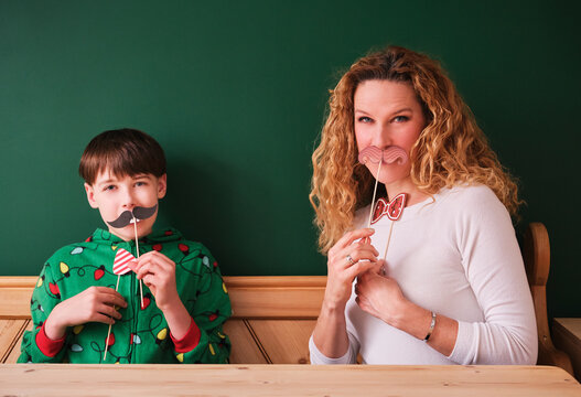Boy and mother playing with mustache props at home
