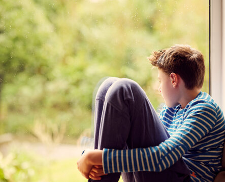 Boy looking through window at home