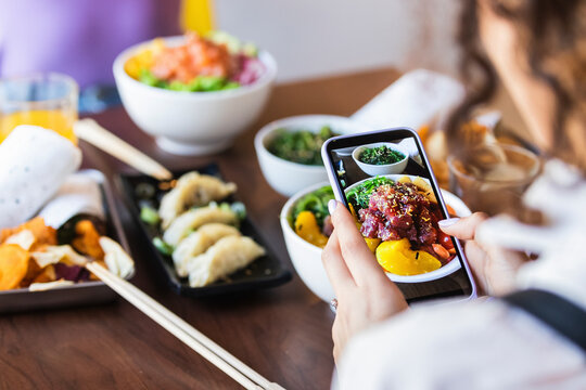 Woman photographing food through mobile phone in restaurant