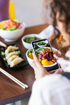 Woman photographing food through smart phone at restaurant