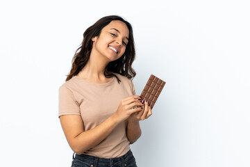 Young woman over isolated white background taking a chocolate tablet and happy