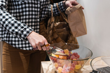 Woman picking candies from glass bowl at supermarket
