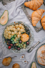 Picnic in vintage style, Grapes and sweets, Fruits and croissants, bread with vintage dishes, decorations on a wooden background near the water, Selective focus, Top view