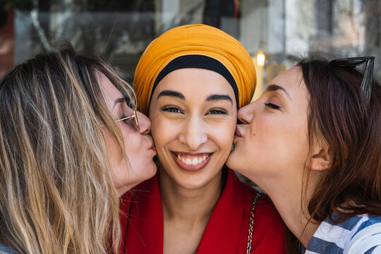Female friends kissing beautiful woman on cheek outdoors