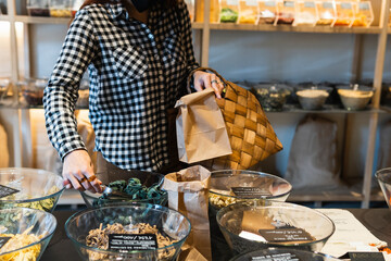 Woman putting spice in paper bag at store