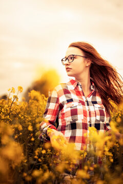 Young woman in a rape field looking sideways