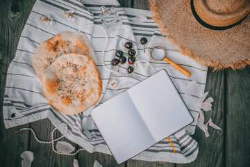 Blank notepad to write, Picnic in vintage style, Fruits and bread with vintage dishes, decorations on a wooden background near the water, Top view