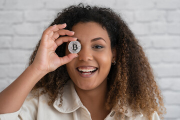 Smiling woman covering eye with silver cryptocurrency