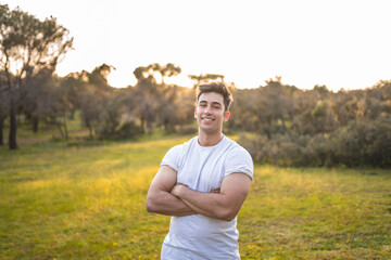 Handsome sports person standing with arms crossed during sunset