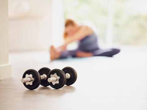 Dumbbells on floor while woman exercising at home