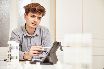 Young male architect working over digital tablet at table