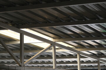 Bottom side of a metal roof and construction frame made of profile metals and white color.