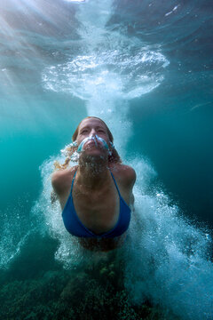 Underwater view of young woman diving in Java Sea