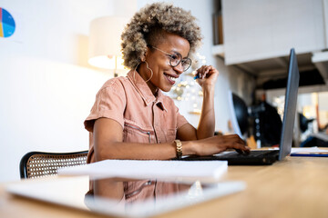 Smiling female professional using laptop while working at home office