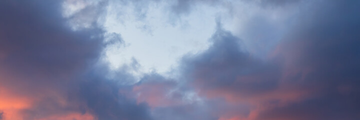 Beautiful sunset sky. Clouds illuminated by red sunlight at sunset. Wide panoramic background for design.