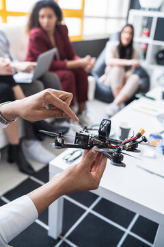 Male engineers explaining drone model with colleagues in office