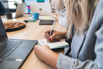 Businesswoman writing notes in diary during meeting in front of laptop at office
