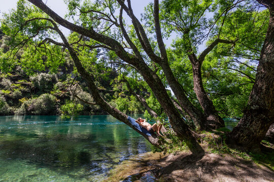 Young man relaxing on bank of Waikato River in summer