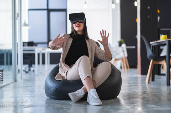 Female professional gesturing while enjoying virtual reality on bean bag in coworking office