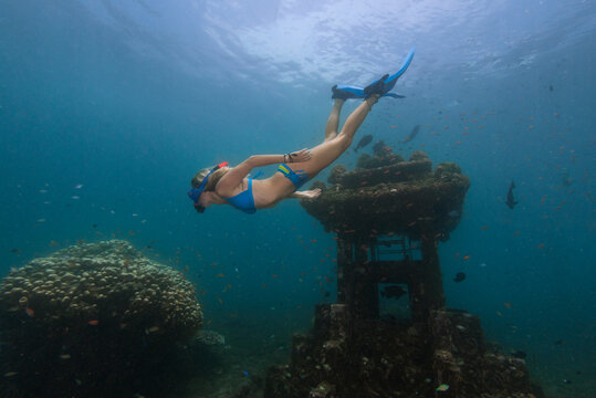 Young woman diving near underwater temple in Java Sea