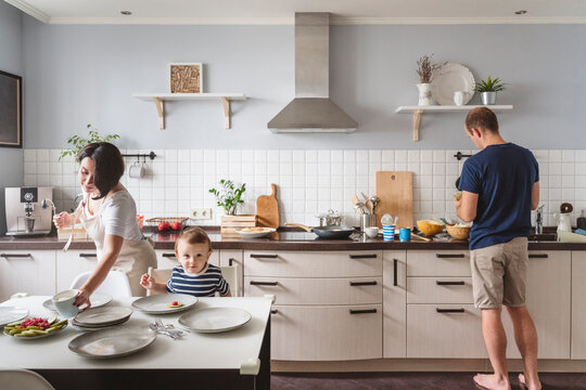 Father and mother with cute son preparing food in kitchen