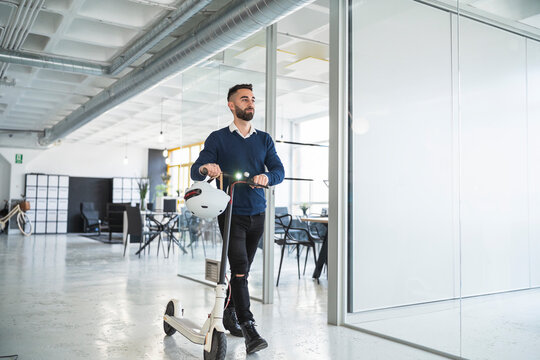 Businessman walking with electric push scooter at coworking office