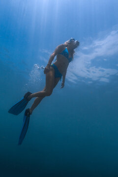 Underwater view of young woman diving in Java Sea
