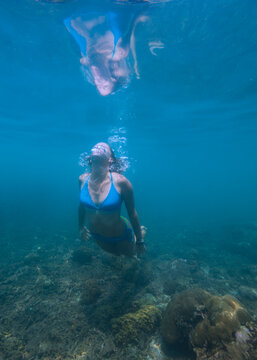 Underwater view of young woman diving in Java Sea
