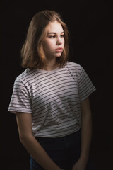 Girl with a long bob haircut in a T-shirt and jeans on a dark background