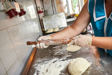 Chef hands sprinkle the Rolling pin with flour before rolling out the dough.
