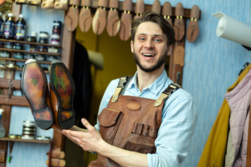Smiling male cobbler showing shoe sole at workshop