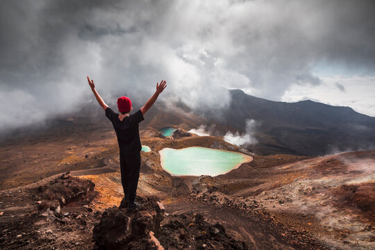 New Zealand,&nbsp;Ruapehu&nbsp;District, Young man standing with raised arms in front of hot spring in&nbsp;Tongariro&nbsp;National Park