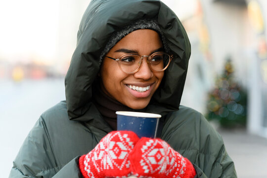 Smiling woman with reusable cup wearing gloves in winter