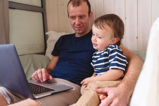 Father working on laptop while sitting with son at home office