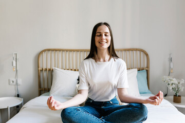 Woman in lotus position on bed at home