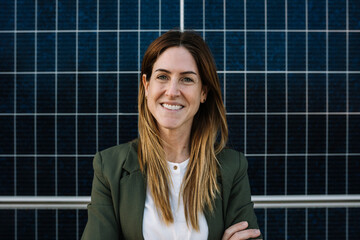 Smiling female entrepreneur in smart casual standing by wall