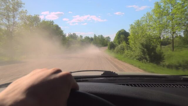 cars race for speed on a dirt gravel road, kicking up dust. camera captures the events of the car in the first person. police are chasing criminals. speed. Dusty road on sunny hot day in countryside.