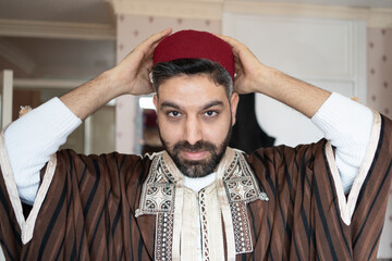 Man in traditional clothing wearing headwear at home