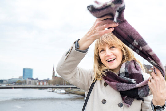 Mature woman smiling while wearing scarf outdoors