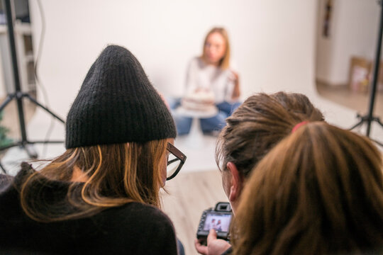 Photographer sharing camera with female coworker in studio