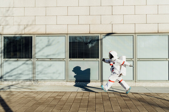 Female astronaut walking at building in city during sunny day