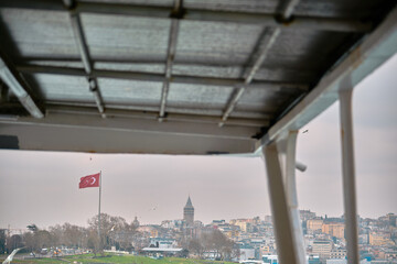 Photo taken from public transportation ferry in istanbul of Lighthouse in bosporus with silhouette of ottoman mosques Hagia sophia (ayasofya) and blue (sultanahmet) mosques background and turkish flag