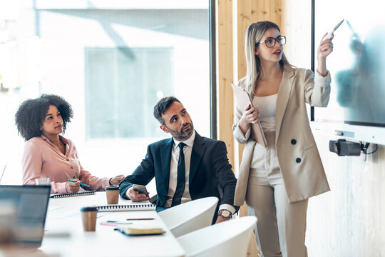 Female professional explaining to colleagues in meeting at office